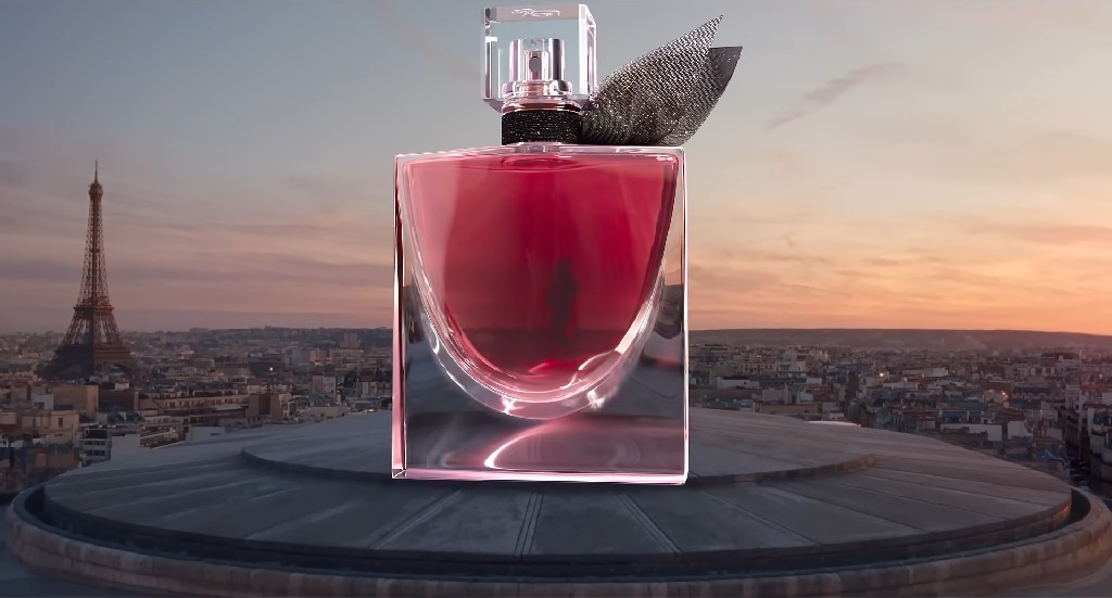 Bočica parfema Lancome La Vie Est Belle postavljena ispred panorame Pariza sa Ajfelovim tornjem u pozadini pri zalasku sunca